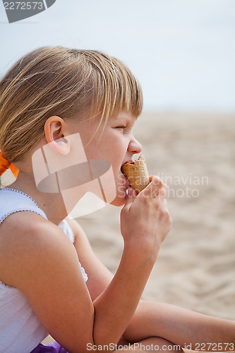 Image of Young girl eating ice cream on beach