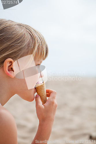 Image of Young girl eating ice cream on beach