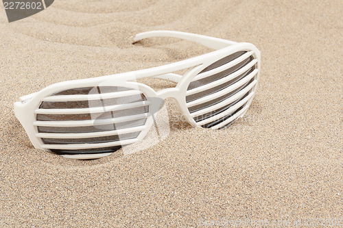 Image of funny sun glasses in sand