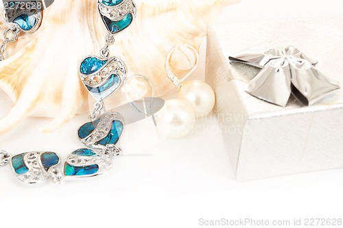 Image of two pearl earrings and sea shells on white