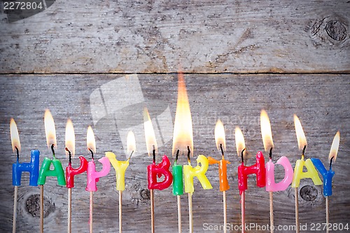 Image of Birthday candles burn against wooden background