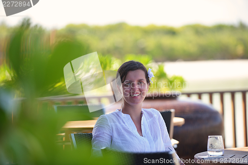 Image of Beautiful young woman with a drink by the sea