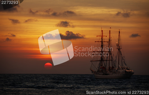 Image of Old sailing ship in the sea at sunset