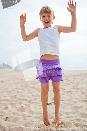 Image of Young girl jumping in sand