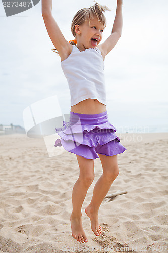 Image of Young girl jumping in sand