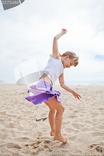 Image of Young girl jumping in sand