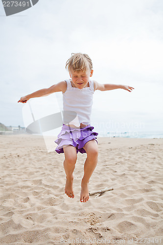 Image of Young girl jumping in sand