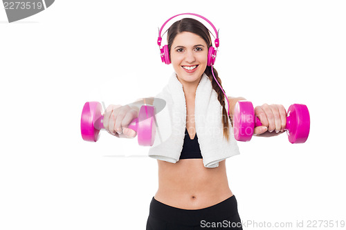 Image of Woman enjoying music while doing dumbbells