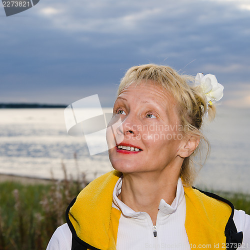 Image of Woman looks at a cloudy sky at the sea