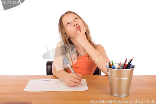 Image of Child sitting at a table trying to make a drawing