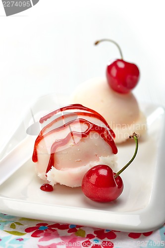 Image of closeup of icecream scoop with sweet sauce and cherry