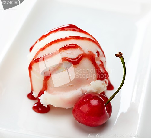 Image of closeup of icecream scoop with sweet sauce and cherry