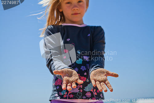 Image of Young girl with sand covered hands