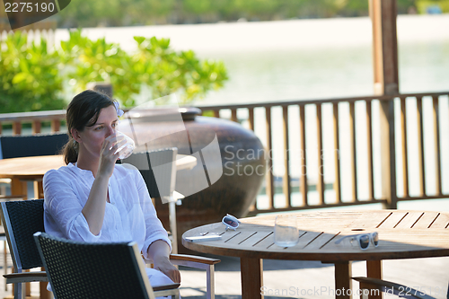 Image of Beautiful young woman with a drink by the sea