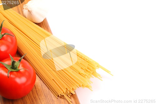 Image of uncooked spaghetti and tomatos on a white background