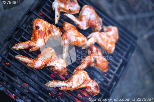 Image of chicken wings being cooked on an outdoor barbeque