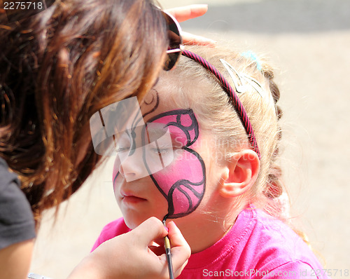 Image of artist paints on face of little girl