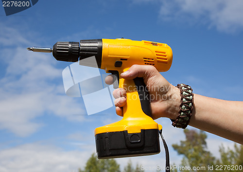 Image of The man is holding a yellow cordless drill