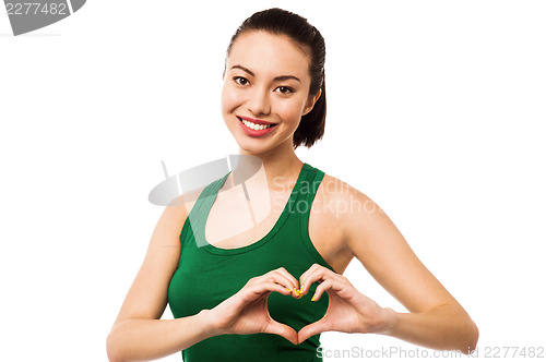 Image of Pretty teenager making heart symbol with hands