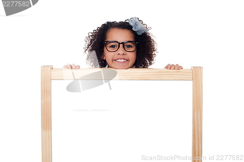 Image of Girl peeping from behind white writing board