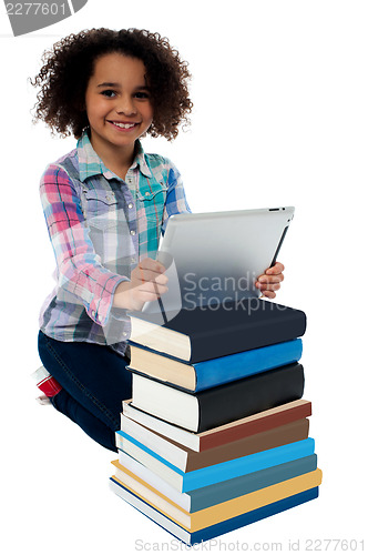 Image of Smiling child busy with tablet pc and books