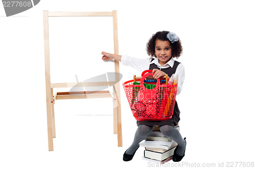 Image of Young cute kid sitting on a pile of books