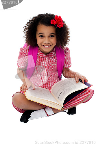 Image of Smiling pretty school girl reading a book
