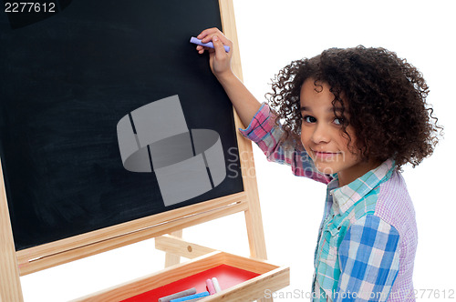 Image of Beautiful little girl writing on classroom board