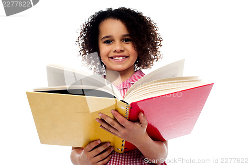 Image of Adorable school girl reading a book with a smile