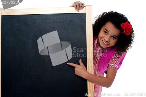 Image of Smiling girl peeps from behind the standing board