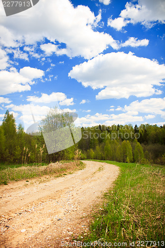 Image of Country road under blue sky with white clouds, vertical shot