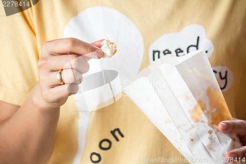 Image of Woman eating popcorn from popcorn paper bag 