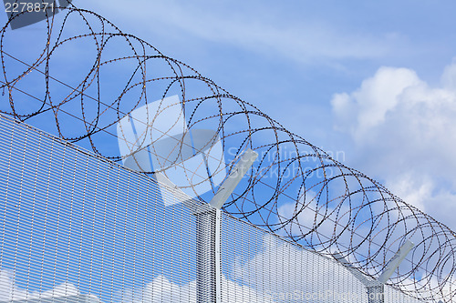 Image of Chain link fence with barbed wire under blue sky