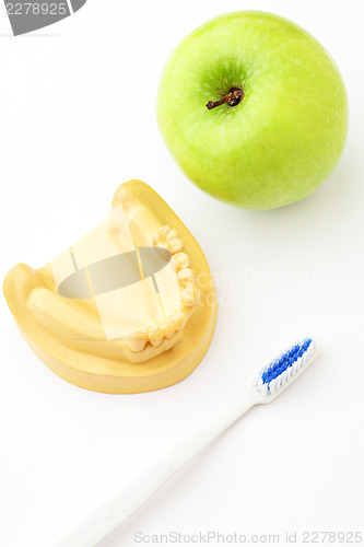 Image of Green apple, toothbrush and denture