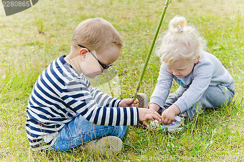 Image of Boy and girl sit on the lawn and what you see in the grass