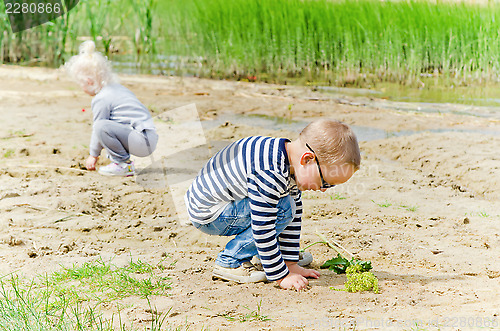 Image of  Boy and girl playing in the sand on the shore of Lake 