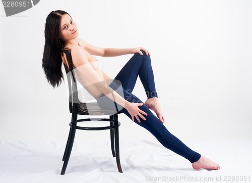 Image of topless woman in jeans sitting on chair