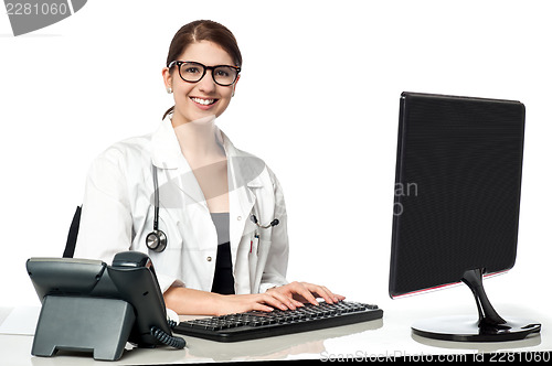 Image of Smiling female doctor working on computer