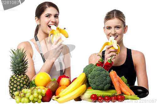 Image of Young smiling girls eating banana