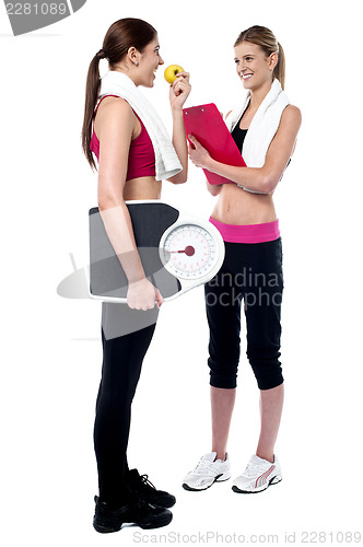 Image of Female trainer writing diet chart for gym member