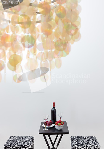 Image of Bottle of red wine on a table, and decorative chandelier