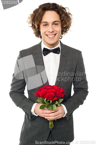 Image of Groom in tuxedo posing with a bouquet