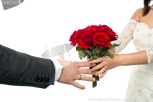 Image of Bride offering rose bouquet to the groom