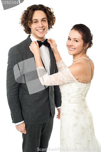 Image of Pretty bride adjusting her man's bowtie