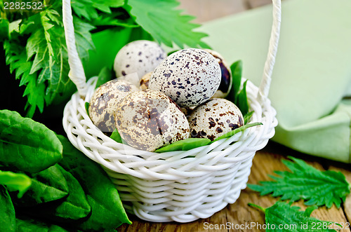Image of Eggs quail in a white basket with nettles and sorrel