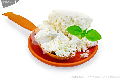 Image of Curd in a spoon and a plate of clay