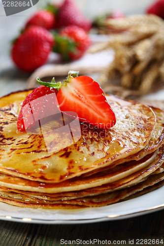 Image of Pancakes with honey and strawberries.