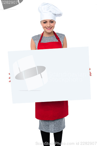 Image of Smiling female chef holding an ad board