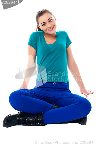 Image of Cute girl sitting casually on the studio floor