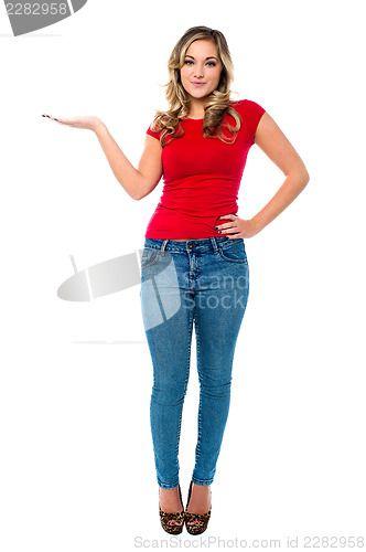Image of Young girl in trendy wear presenting something